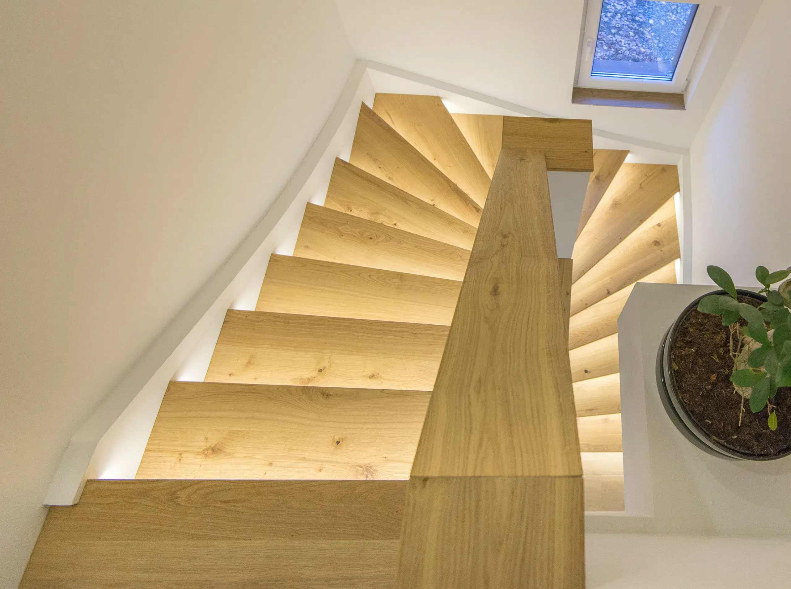 Eine Wendeltreppe mit Treppenstufen aus Holz und integrierter Beleuchtung in einem Haus.