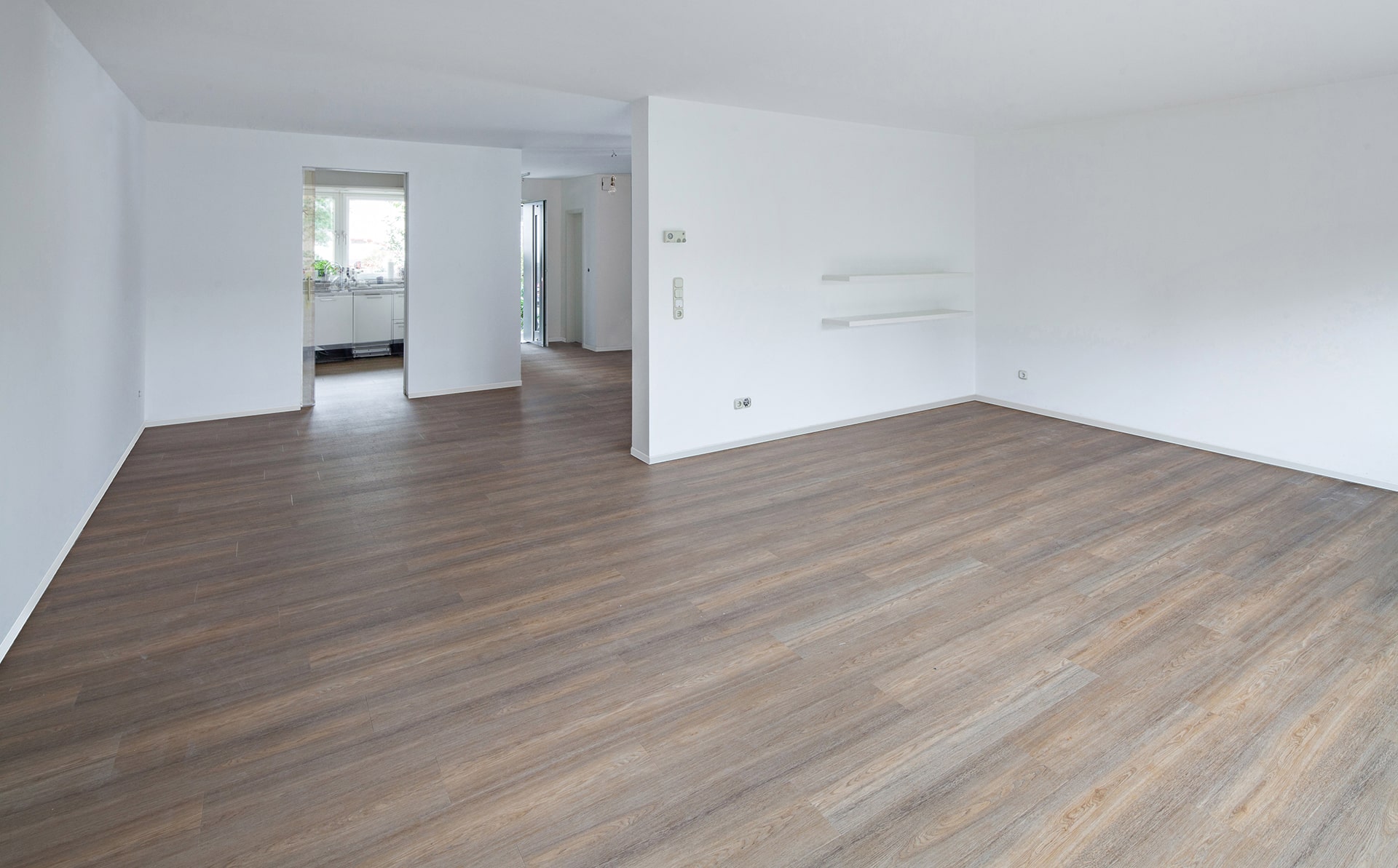 Ein leerer Raum mit Holzböden und weißen Wänden.