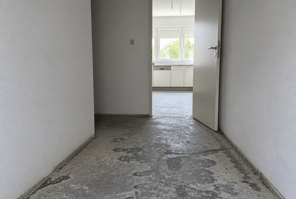 Vorher: Flur mit rissigem Estrich und Kleberresten