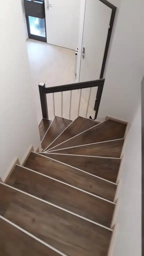 Gewendelte Treppe mit Designbelag-Stufen in dunkler Holzoptik
