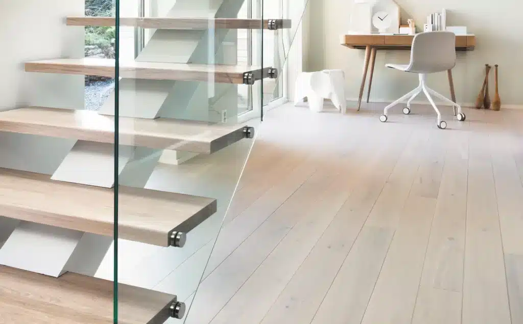 Freitragende helle Holztreppe mit Glasgelaender vor Arbeitszimmer