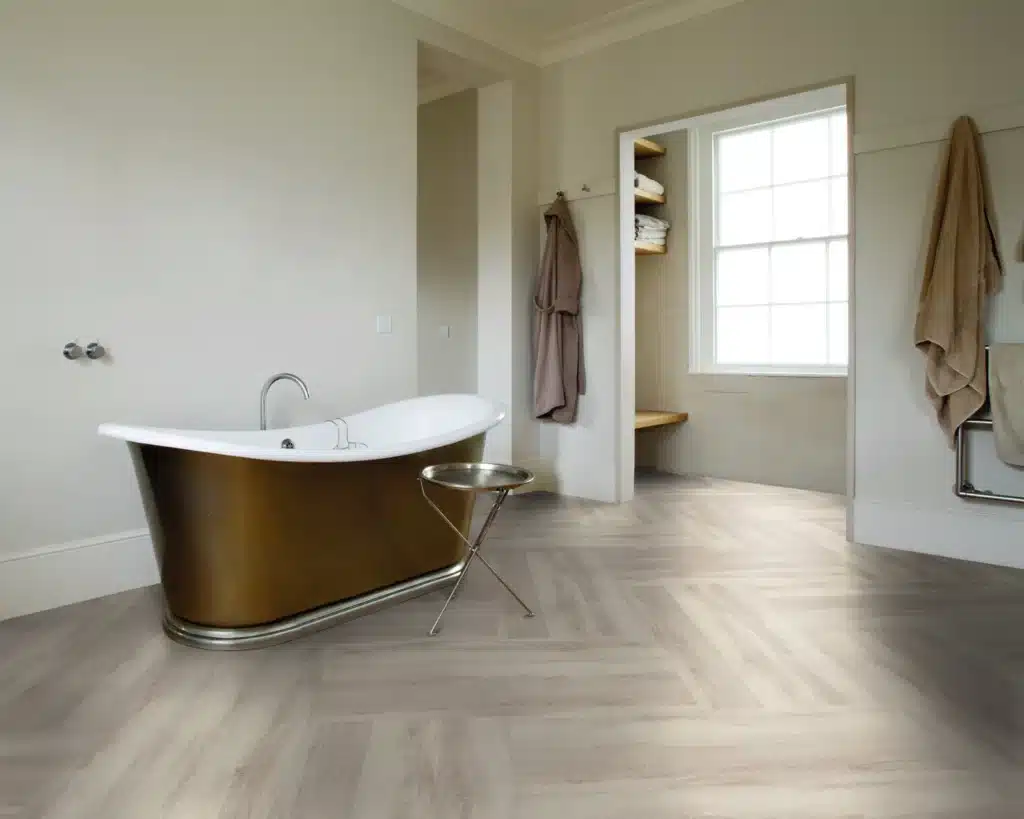 Badezimmer mit Vinylboden in heller Fischgraet-Verlegung und freistehender Wanne
