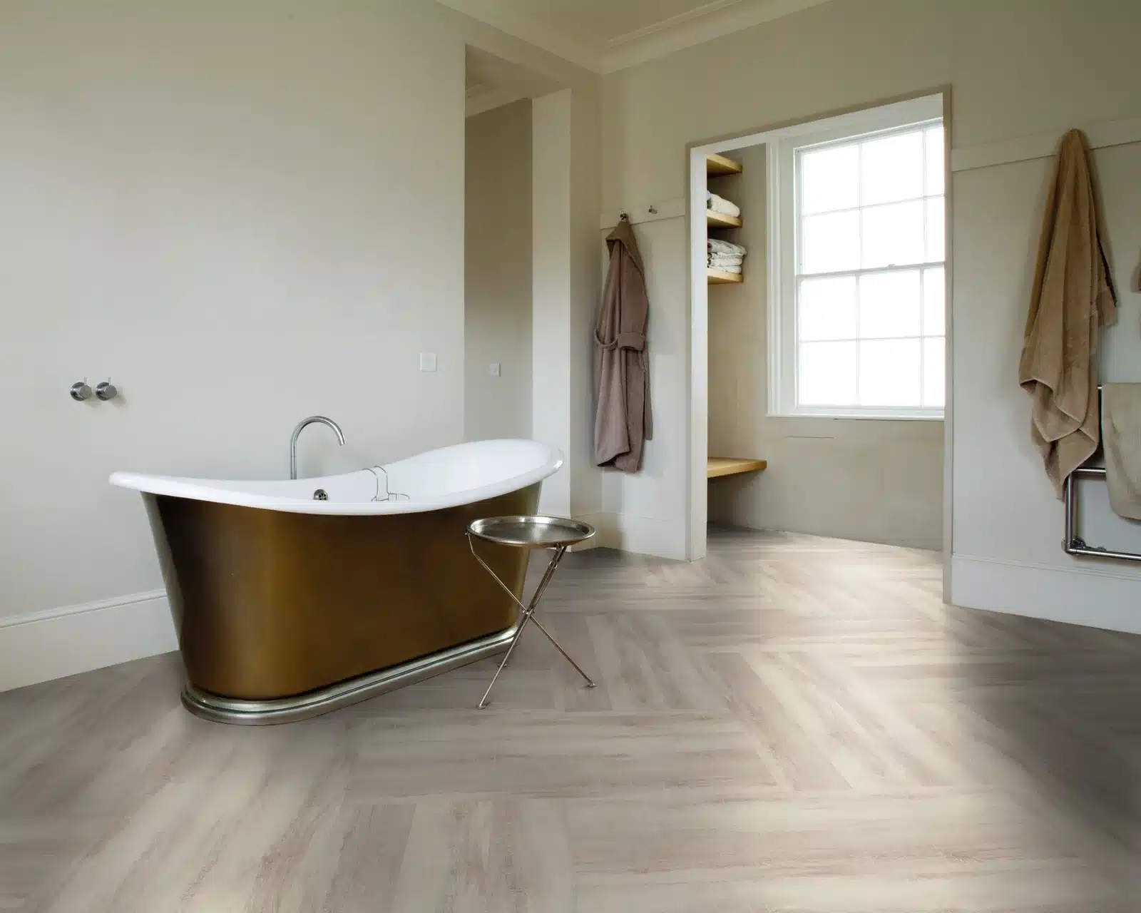 Badezimmer mit Vinylboden in heller Fischgraet-Verlegung und freistehender Wanne