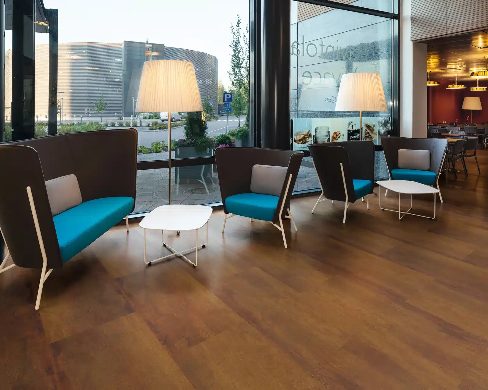 Lounge mit Vinylboden in Rost-Metalloptik und petrolfarbenen Sesseln